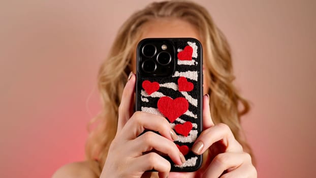 A young woman with red lipstick takes a selfie with long blond hair and makeup. The girl is smiling and looking at the camera close-up