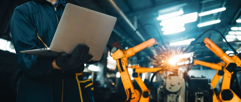 MLB Engineer use advanced robotic software to control industry robot arm in factory. Automation manufacturing process controlled by specialist using IOT software connected to internet network.