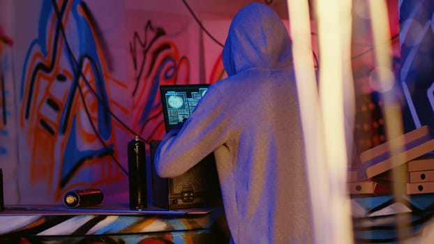 Close up shot of hacker in underground bunker using network vulnerabilities to exploit servers, trying to break computer systems at night. African American cybercriminal breaching networks
