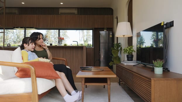 Grandmother and granddaughter together watch interesting entertainment media on TV. Old senior use technology communicate with young generation cross generation gap strengthen family bond. Divergence.