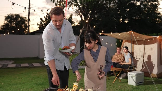 Family celebrate holiday in garden, Father and child grill food for family member. Outdoor camping activity relax with tasty meal and spend time with young generation cross generation gap. Divergence.
