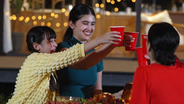 Family gather for holiday celebration. All family member cheers beverage glass to celebrate. Outdoor camping activity relax with food and spend time with relatives cross generation gap. Divergence.