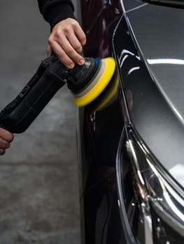 A master polishes the surface of a car body