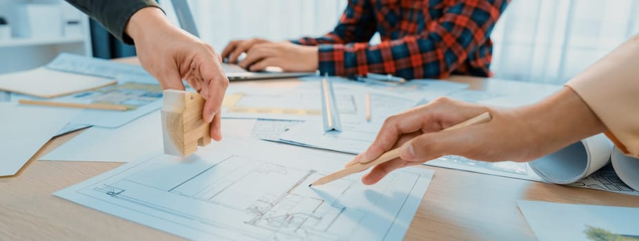 Skilled architect team using architectural equipment during colleague discussion about building design at meeting table with blueprint scatter around. Closeup. Focus on hand. Delineation.