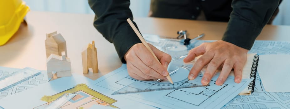 Professional engineer measuring the blueprint. Professional engineer working architectural project at studio on a table with yellow helmet and architectural equipment scatter around. Delineation.