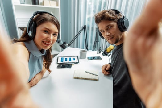 Host channel broadcasters wearing headsets making self photo shooting to pose, live streaming with listeners surround set of live stream social media record smartphone at modern studio. Postulate.