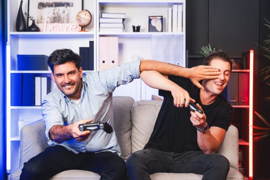 Winner and loser players of buddy friend gamers playing video game on TV using joysticks in studio room with neon blue light. Comfy living indoor at home place with cheerful fighting winner. Sellable.