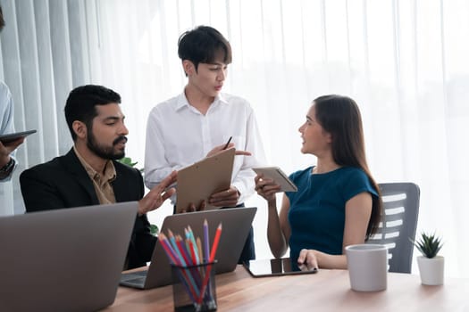 Professional Asian employee work together as team in corporate office, discussing business plans and data to achieve success on desk with laptop. Modern office worker teamwork concept. Concord