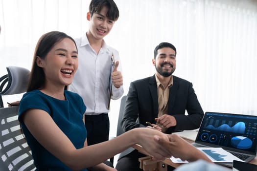 Diverse coworkers celebrate success with handshake and teamwork in corporate workplace. Multicultural team of happy professionals united in solidarity by handshaking in office. Concord