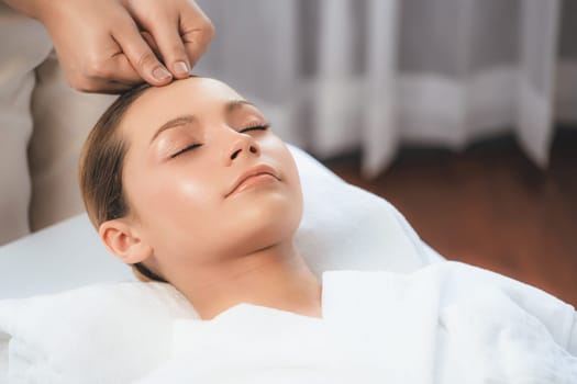 Caucasian woman enjoying relaxing anti-stress head massage and pampering facial beauty skin recreation leisure in dayspa modern light ambient at luxury resort or hotel spa salon. Quiescent