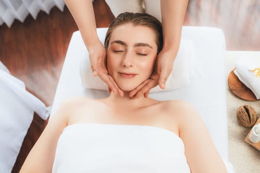 Caucasian woman enjoying relaxing anti-stress head massage and pampering facial beauty skin recreation leisure in dayspa modern light ambient at luxury resort or hotel spa salon. Quiescent