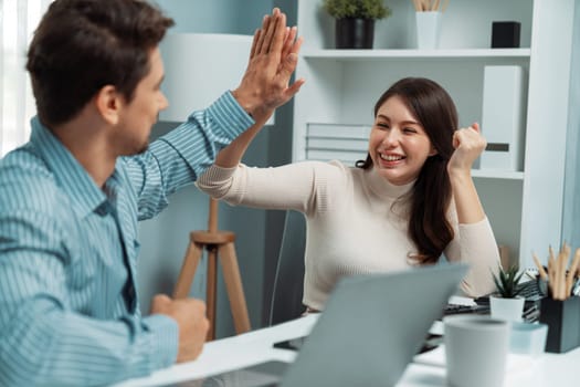 Smiling happy coworkers making hand high five also raising fist up of successful creative business project plan with highest profit value job in casual day at modern office at morning time. Postulate.