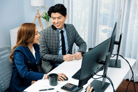 Business Asian coworkers analyzing marketing report project on two screen computer comparing value stock exchange database online report at modern office. Analyzing value investment company. Infobahn.