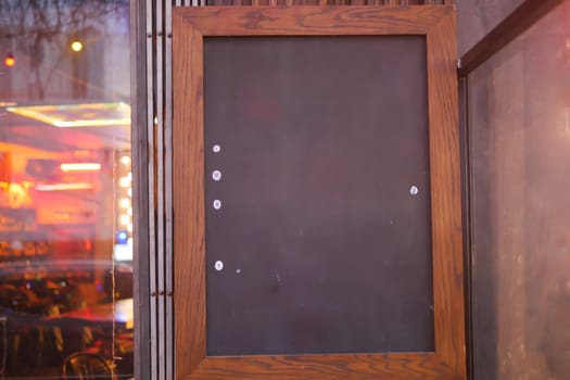 Empty wooden blackboard mockup standing outdoors in front of cafe .