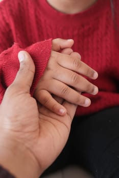 father holding hand of baby child, close up