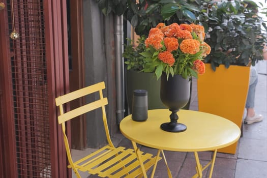 A yellow table with a vase filled with bright orange flowers adorning it, adding a touch of vibrant color to the room