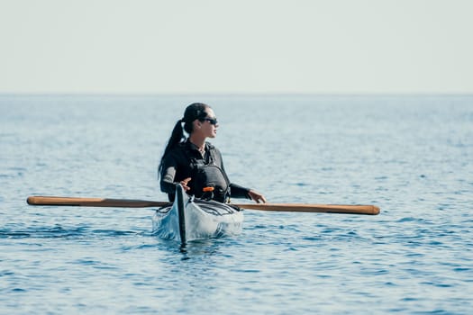 Happy smiling woman in kayak on ocean, paddling with wooden oar. Calm sea water and horizon in background