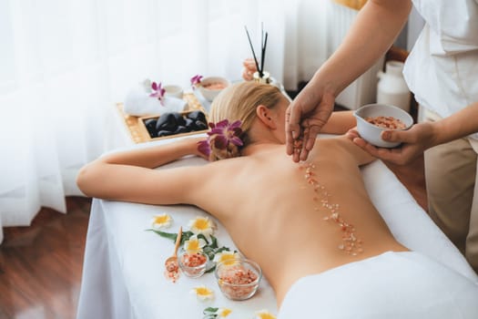 Woman customer having exfoliation treatment in luxury spa salon with warmth candle light ambient. Salt scrub beauty treatment in health spa body scrub. Quiescent