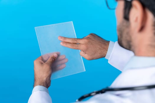 Back view of smart doctor looking application form while standing at blue background. Professional caucasian doctor diagnosis disease while looking at chart holding in hands. Close up. Deviation.