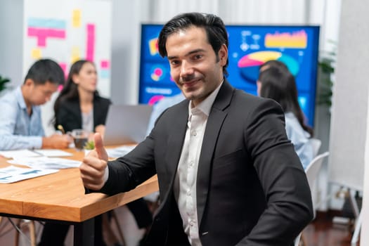 Portrait of businessman or analyst looking at camera with his colleague analyzing data analysis in dynamic business strategy investment planning meeting. Meticulous