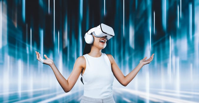 Female standing and wearing white VR headset and white sleeveless connect metaverse, future technology creating cyberspace community. She enjoy look fantasy abstract light around her. Hallucination.