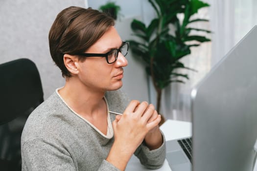 Smart office worker looking camera with serious face of focusing facial good-looking wearing glasses sitting at modern office. Concept of working businessman in casual day on new profile. Pecuniary.