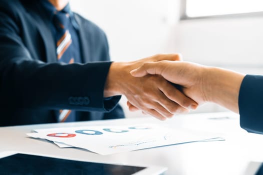 Business people agreement concept. Businessman and Asian businesswoman do handshake in the office. uds