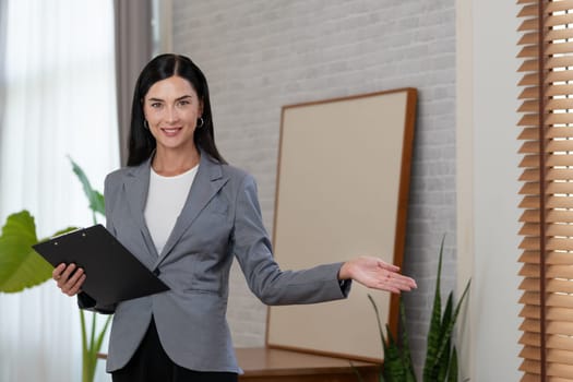 Portrait of happy and smiling female psychologist portrait sitting on arm chair in psychiatrist office or therapy room. Friendly and professional mental healthcare counselor and therapist. Blithe