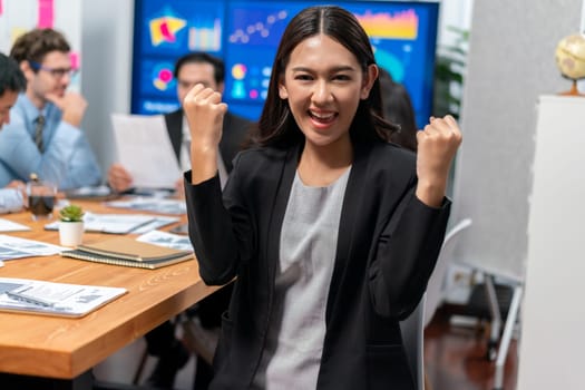 Portrait of happy young asian businesswoman or analyst looking at camera with her colleague analyzing data analysis in dynamic business strategy investment planning meeting. Meticulous