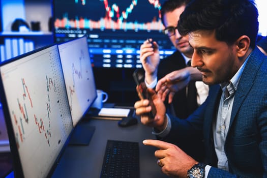 Two stock exchange traders researching data on smartphone and laptop screen server of dynamic digital currency. Investors analyzing market stock at decorative neon blue-light of workplace. Sellable.