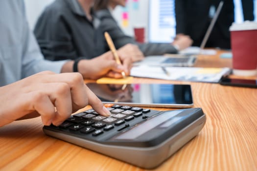 Multiracial analyst team use calculator and data science BI Fintech dashboard data to analyze financial report on office meeting table. Diverse business people for analytic teamwork. Concord