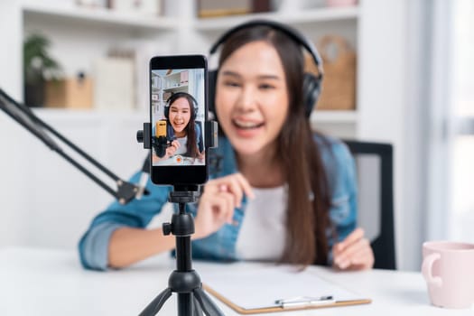 Selective focus phone in host channel of young beautiful Asian in creative broadcaster talking online explaining to promote marketing or consultant in daily life with listener at studio. Stratagem.