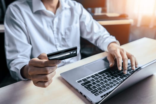 Young man use credit card for shopping payment online on laptop computer application or website. E-commerce and online shopping concept. uds