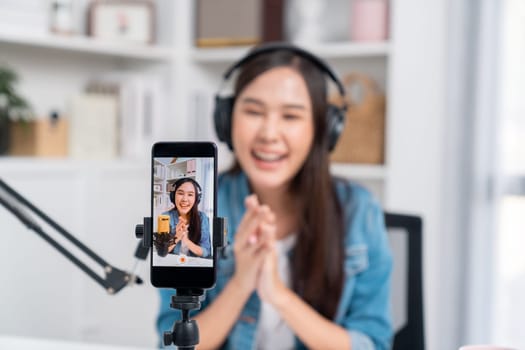 Selective focus phone in host channel of young beautiful Asian in creative broadcaster talking online explaining to promote marketing or consultant in daily life with listener at studio. Stratagem.