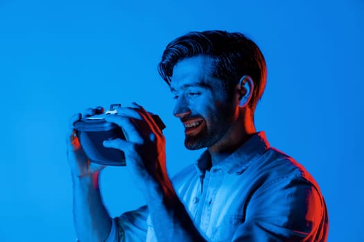 Close up of man holding VR headset and using to connect metaverse. Man preparing for using wearing virtual reality headset device and casual shirt while standing at neon light. Technology. Deviation.