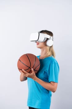 Girl wearing visual reality glasses and casual cloth and holding basketball. Caucasian woman playing basketball while standing at pink background at sport arena hologram. Innovation. Contraption.