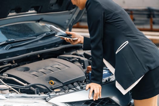 Young businesswoman whose car breakdown uses mobile phone to call for roadside assistance service. Travel and transportation vehicle problem. uds