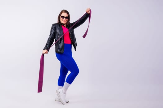 Strong female working with resistance band. Photo of model in fashionable sportswear on grey background.