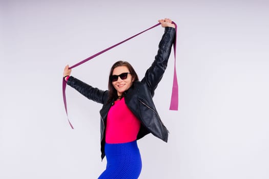 Strong female working with resistance band. Photo of model in fashionable sportswear on grey background.