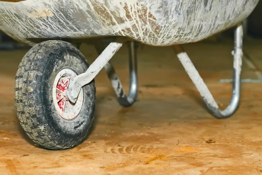 a small cart with a single wheel at the front and two supporting legs and two handles at the rear