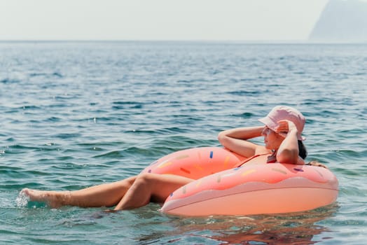 Summer Vacation Woman in hat floats on an inflatable donut mattress, a water toy swim ring. Unrecognizable young woman relaxing and enjoying family summer travel holidays vacation on the sea