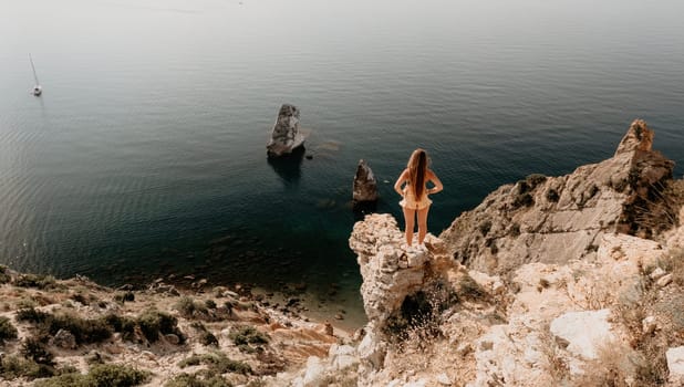 Woman travel sea. Happy tourist taking picture outdoors for memories. Woman traveler looks at the edge of the cliff on the sea bay of mountains, sharing travel adventure journey.