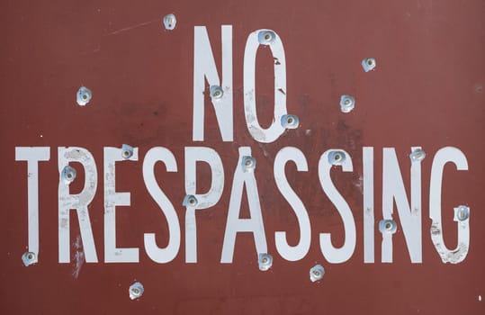 A No Trespassing Sign With Bullet Marks