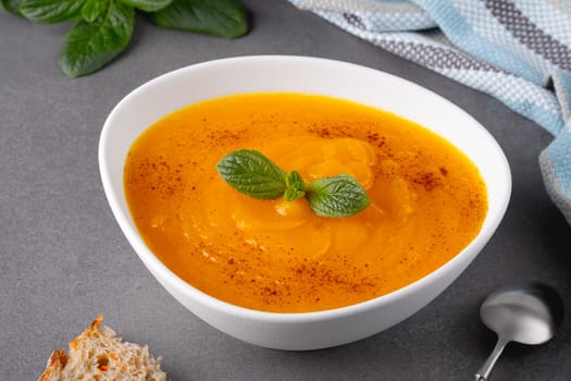 Pumpkin and carrot soup on grey background.