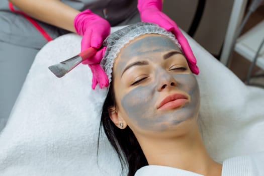 Cosmetician Applying Facial Mask On Face Of Woman.