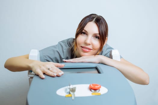 Female cosmetologist in a medical coat holds a working part of the modern laser epilator in her hands and poses for a photo. Laser epilation treatment in cosmetic beauty clinic