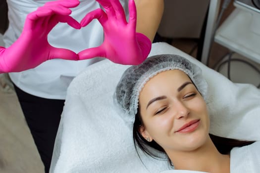 Medicine and cosmetology.Close-up doctor holds above the patient's head a gesture in the form of a heart in latex gloves.