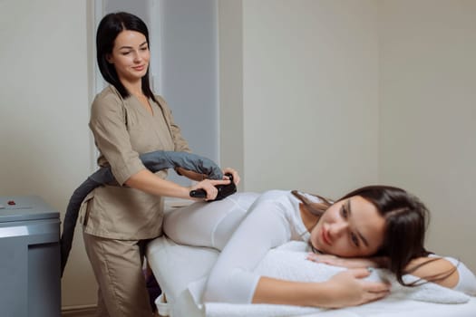 Woman in special white suit getting anti cellulite massage in a spa salon. LPG, and body contouring treatment in clinic.Reset body weight with LPG massage.