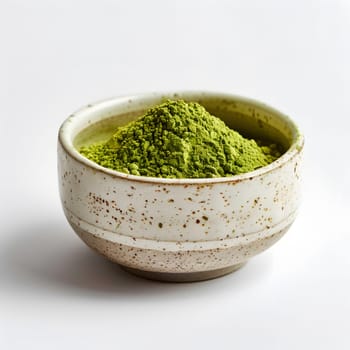 A white dishware bowl is filled with vibrant green leaf vegetable powder on a white serveware surface, ready to be used as an ingredient in a delicious cuisine dish or green sauce