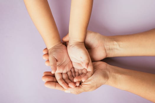 Top view of parents and kid holding empty hands together on color background. Celebrating Family Day embracing togetherness support and generations.